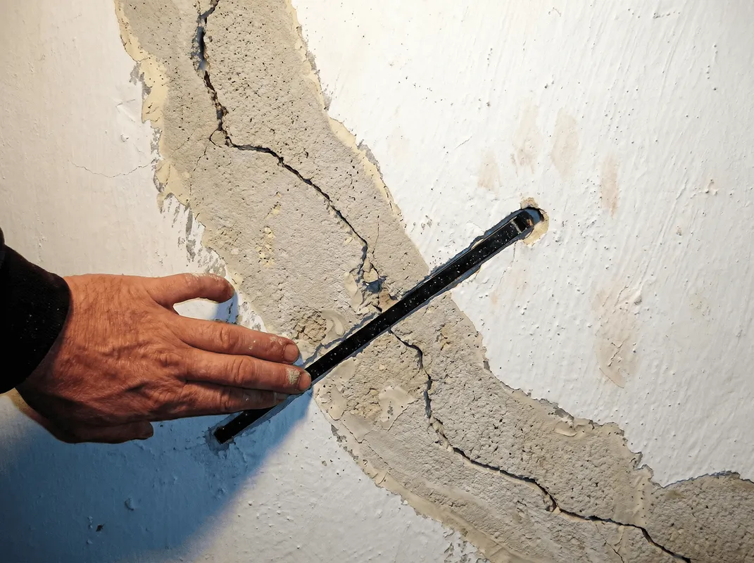 A wall with a large crack is being inspected by a professional in Jackson, MS